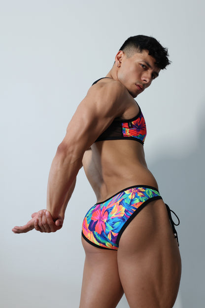 Fabian Divani modeling a sheer floral mesh crop top and swim brief set—handmade by Fabi —posed in front of a white wall