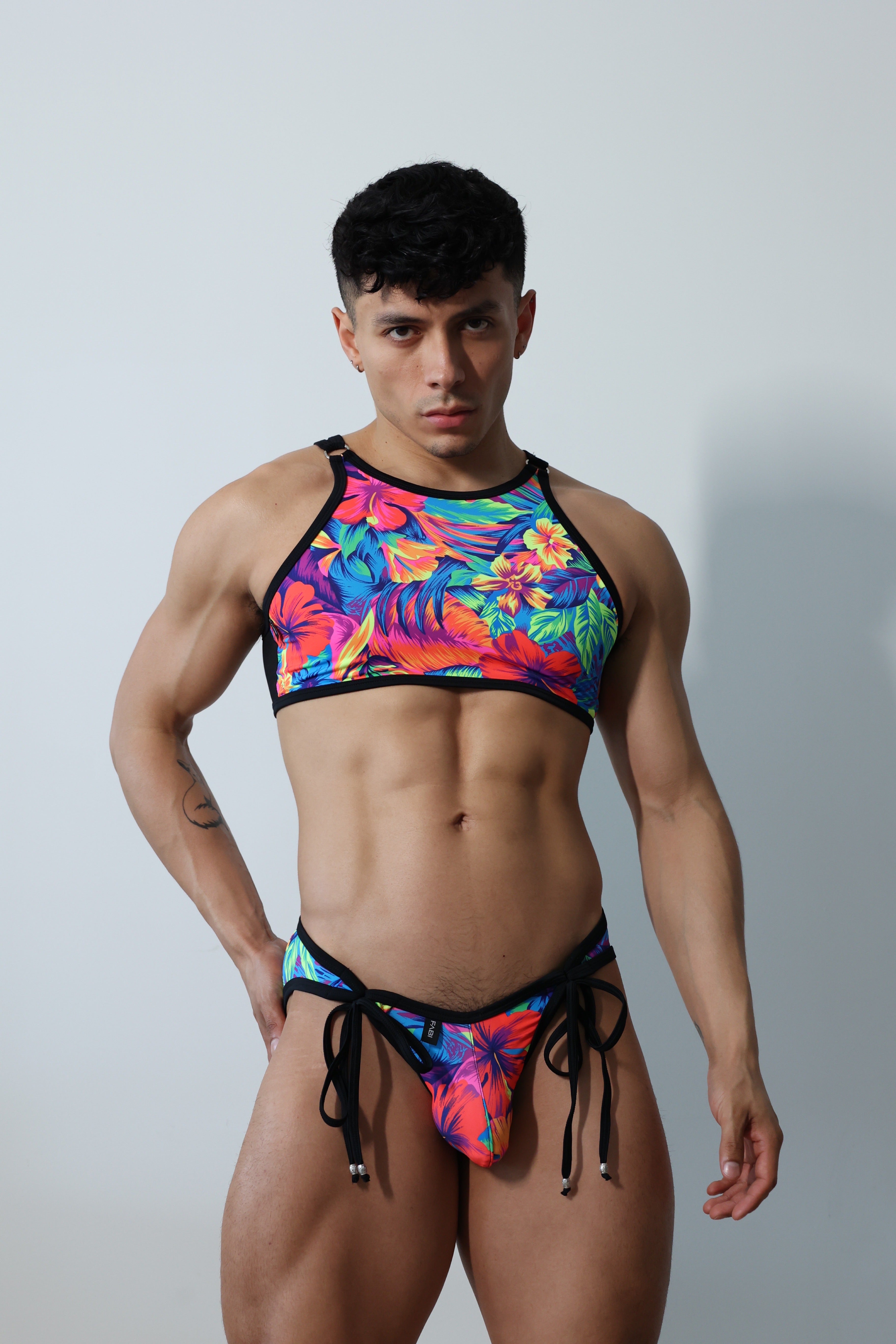 Fabian Divani modeling a sheer floral mesh crop top and swim brief set—handmade by Fabi —posed in front of a white wall