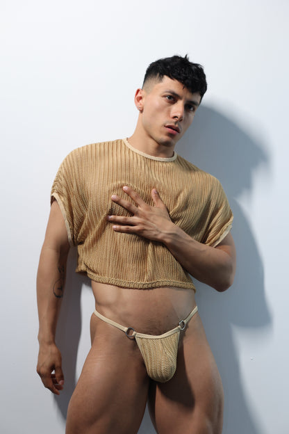 Fabian Divani modeling a sheer natural mesh crop top and G-string underwear set— handmade men's underwear — posed in front of a white wall