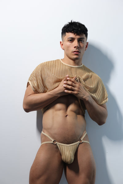 Fabian Divani modeling a sheer natural mesh crop top and string jockstrap underwear set— handmade men's underwear — posed in front of a white wall