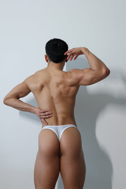 Fabian Divani modeling a sheer Pinstripe mesh crop top and swim brief set—handmade men's swimwear—posed in front of a white wall