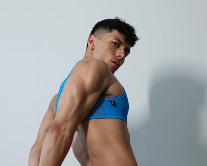 Fabian Divani modeling a  ring crop top — handmade by Fabi — posed in front of a white brick wall