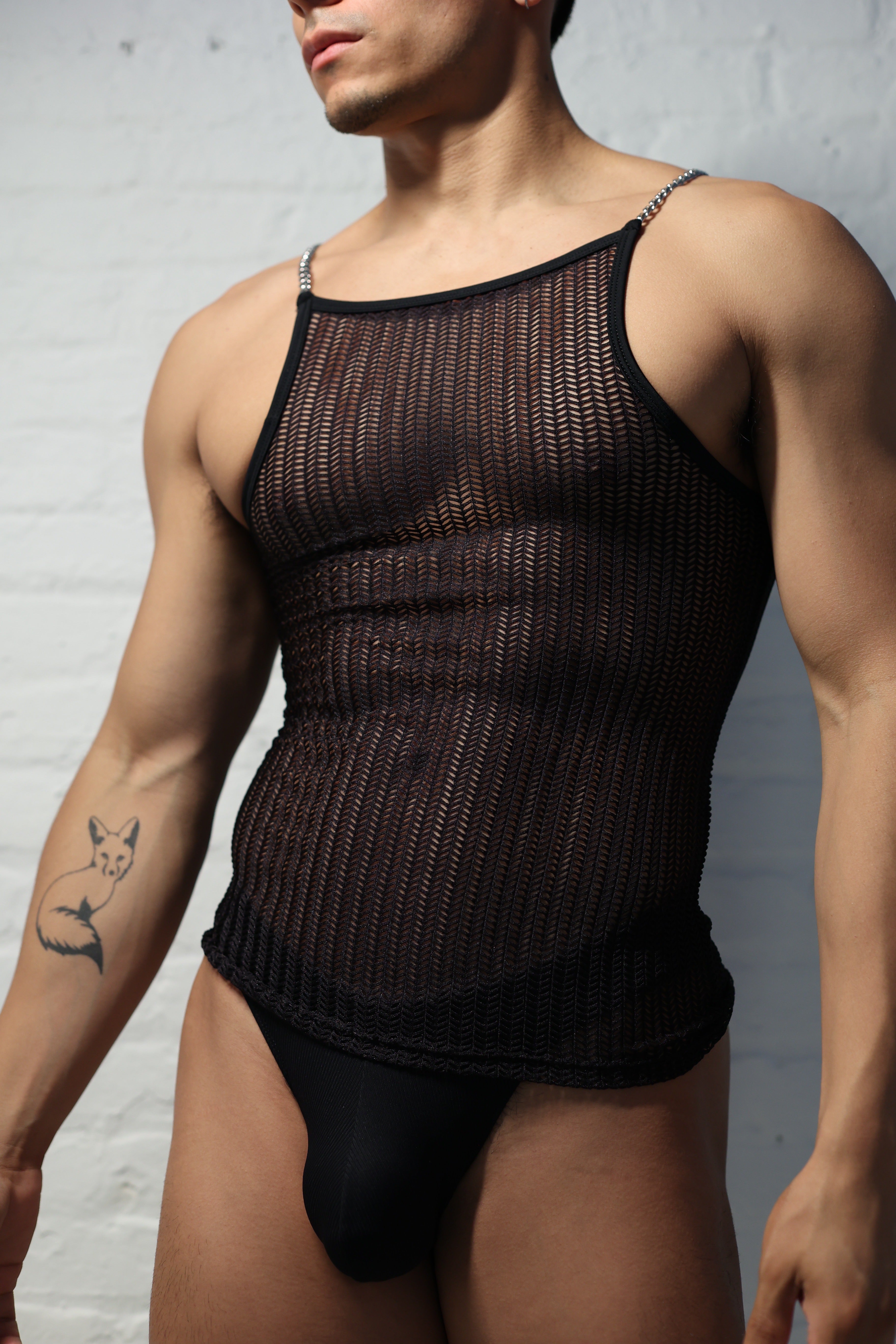 Model wearing black netted mesh tank top with metal chain straps from Fabian Divani Studio showing textured pattern detail