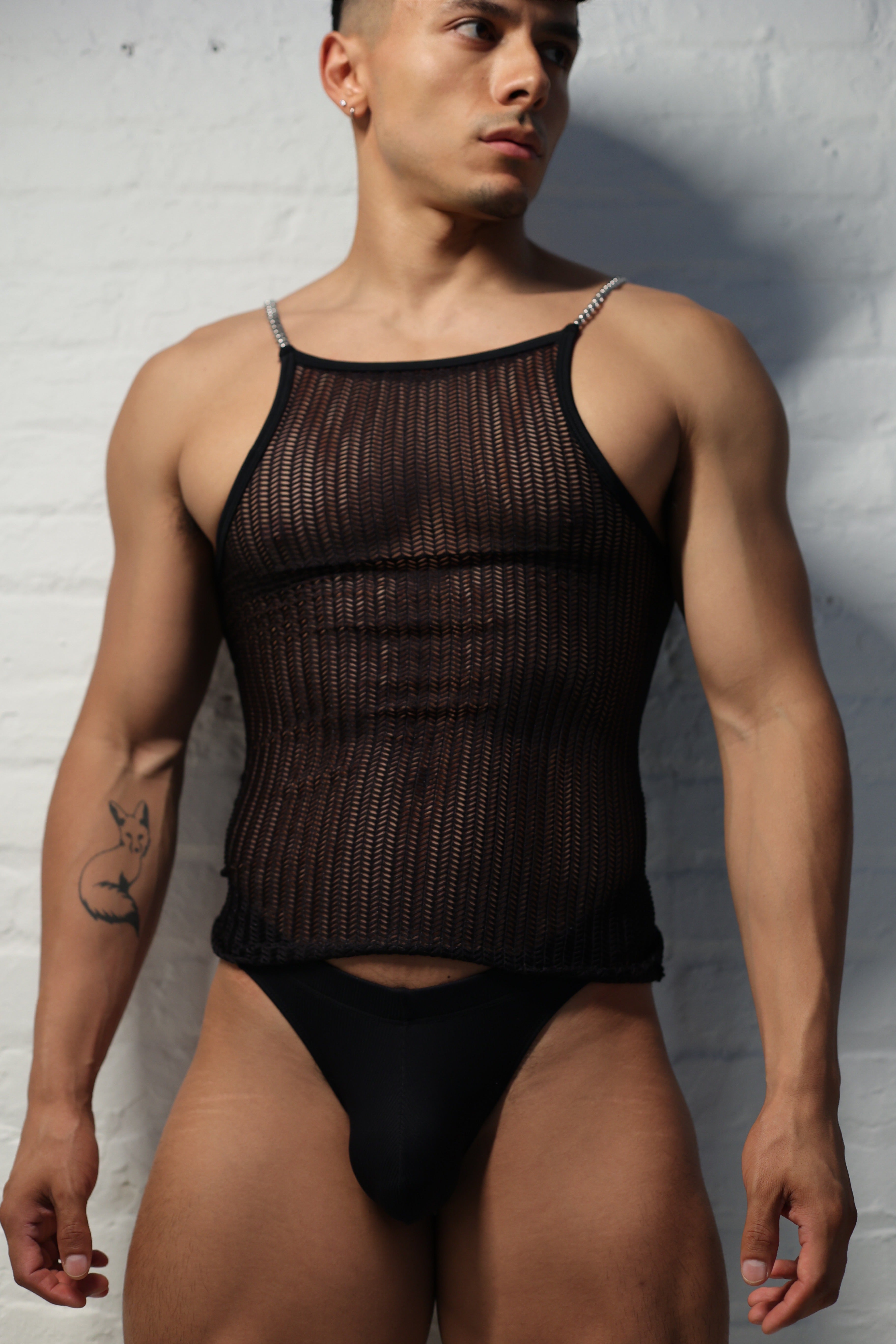 Model wearing black netted mesh tank top with metal chain straps from Fabian Divani Studio showing textured pattern detail