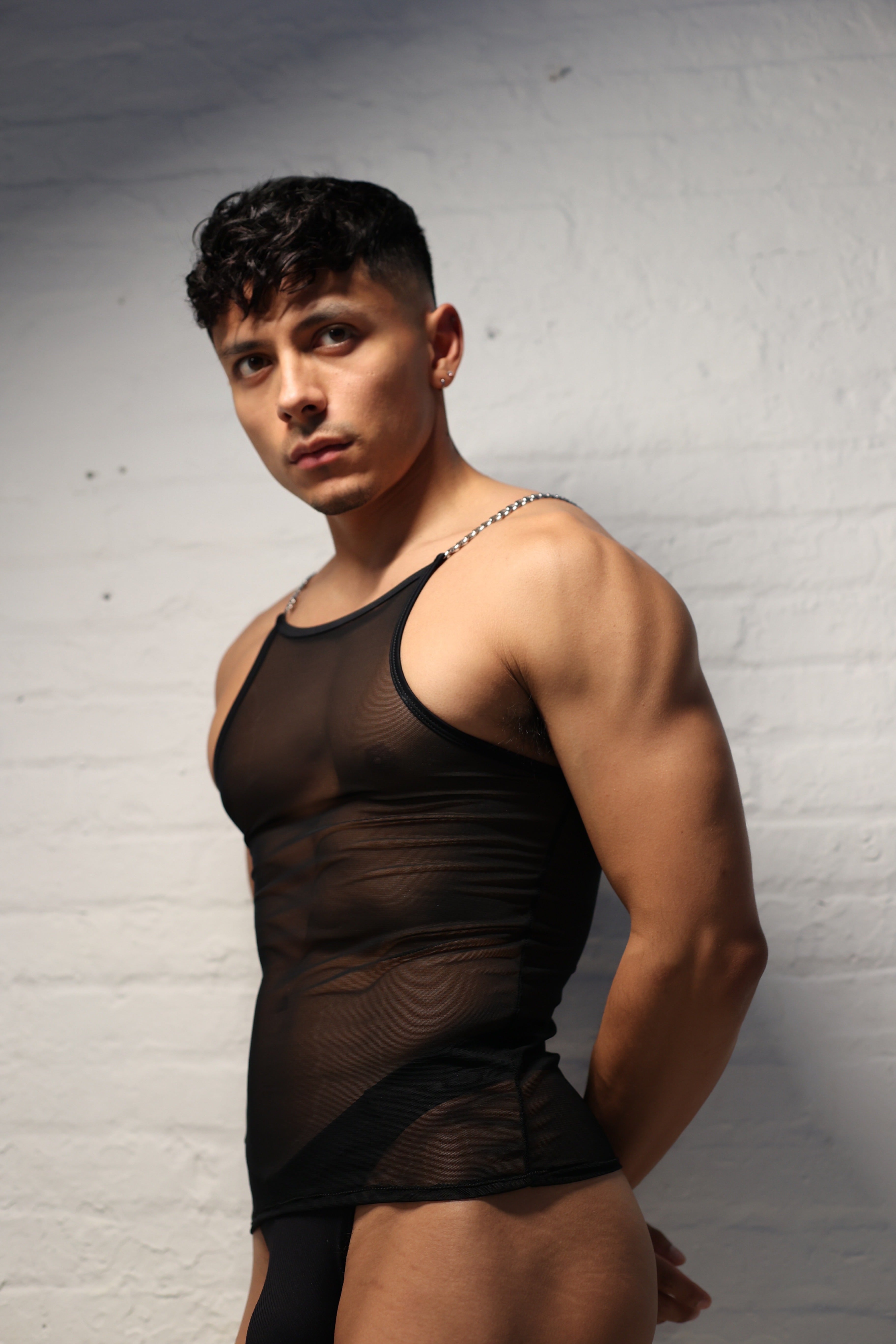 Model wearing black sheer mesh tank top with metal chain straps from Fabian Divani Studio mens collection