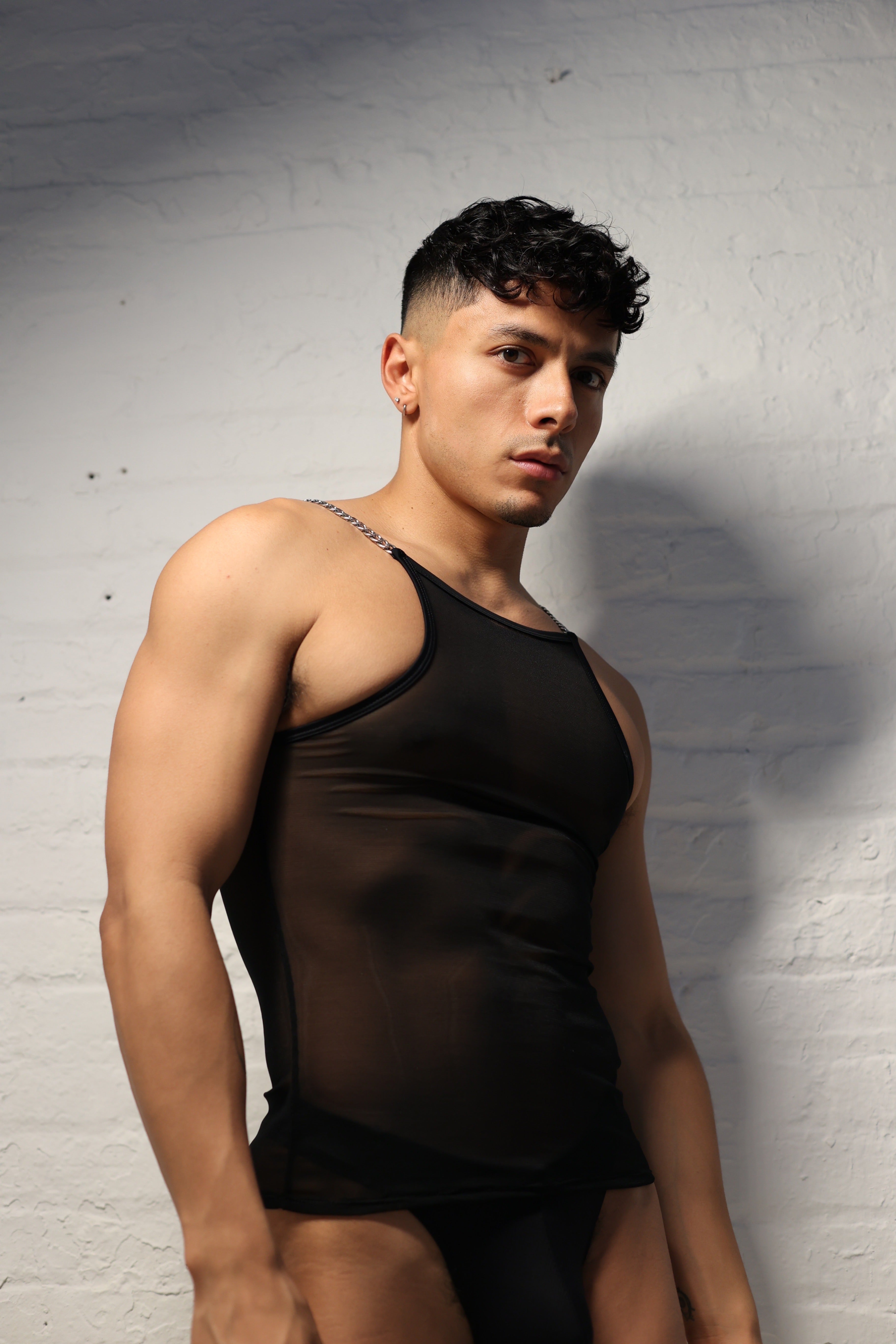 Model wearing black sheer mesh tank top with metal chain straps from Fabian Divani Studio mens collection
