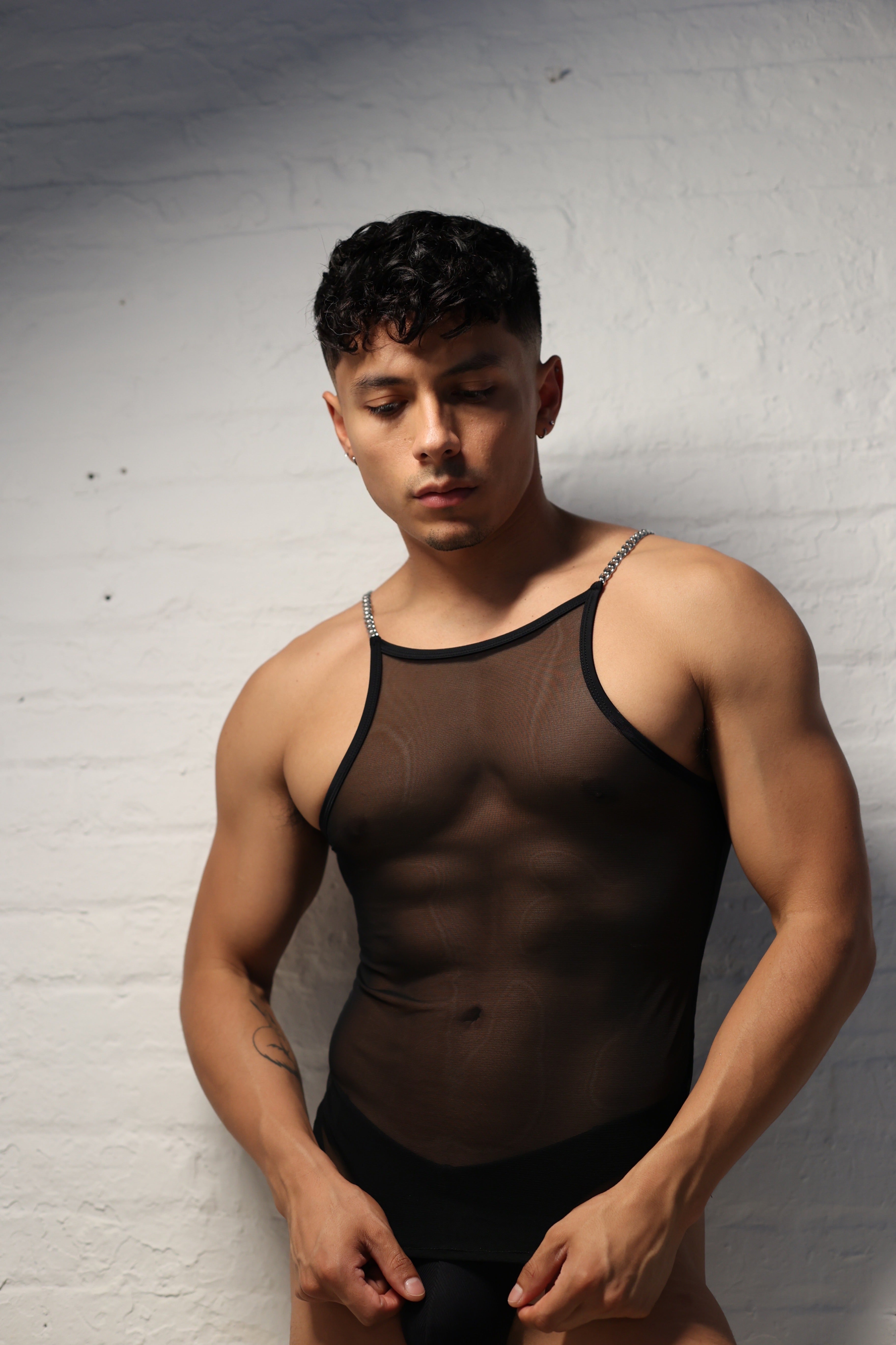 Model wearing black sheer mesh tank top with metal chain straps from Fabian Divani Studio mens collection