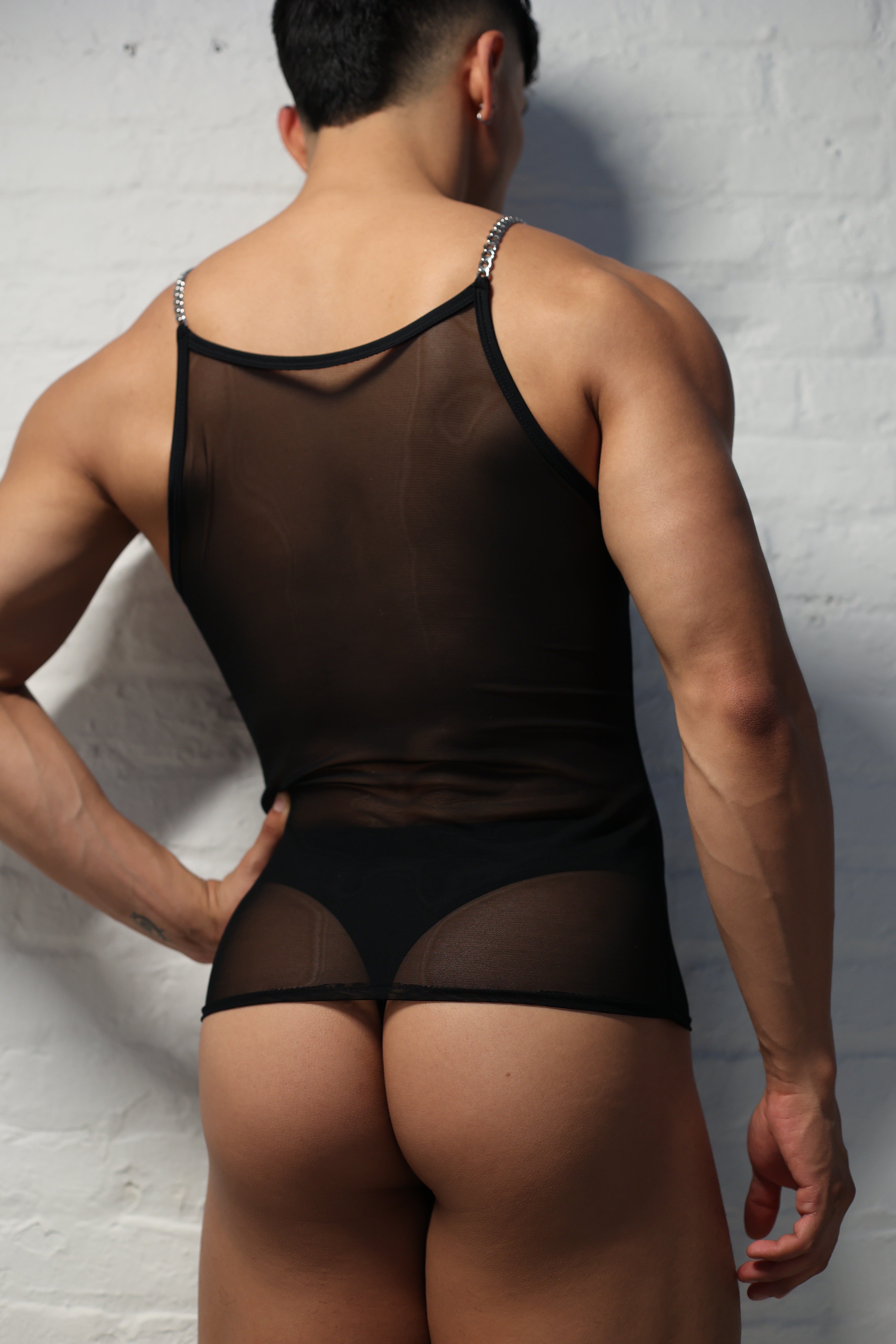 Model wearing black sheer mesh tank top with metal chain straps from Fabian Divani Studio mens collection